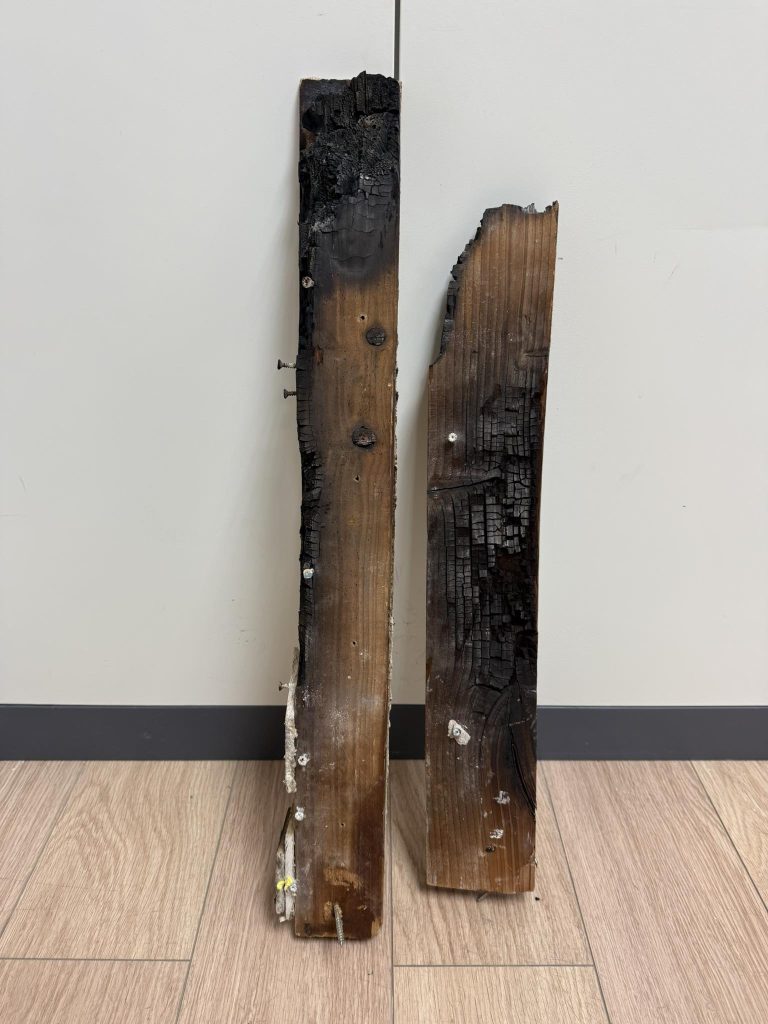 Heat-damaged charred wood removed from a stove installation due to poor clearance to combustible materials.