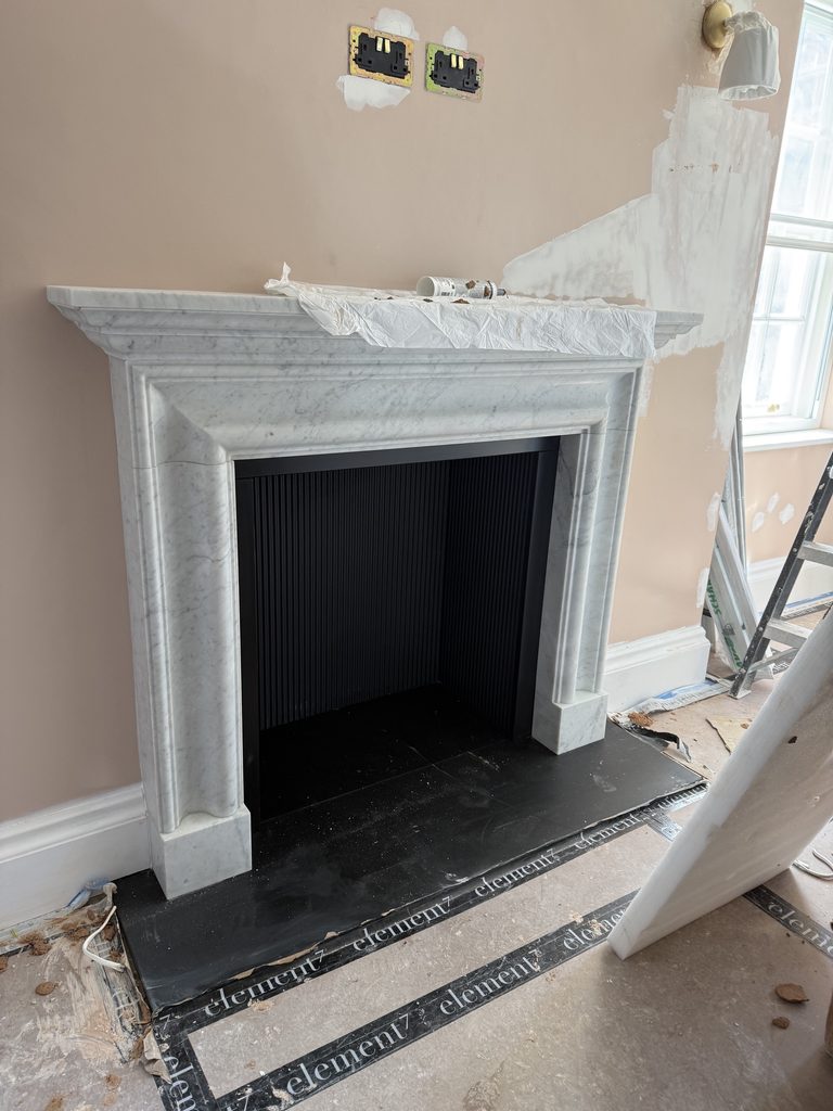 Carrara marble Bolection fireplace with cast iron chamber lining in Mayfair London